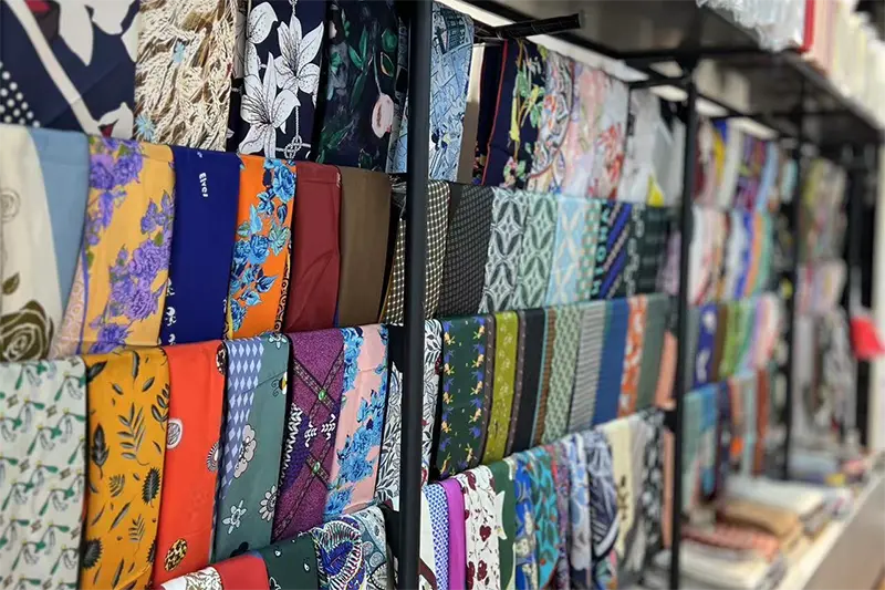 Printed silk scarves hanging in rows on a display rack