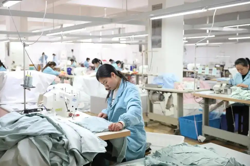 workers sewing silk sleepwear garments in factory workshop