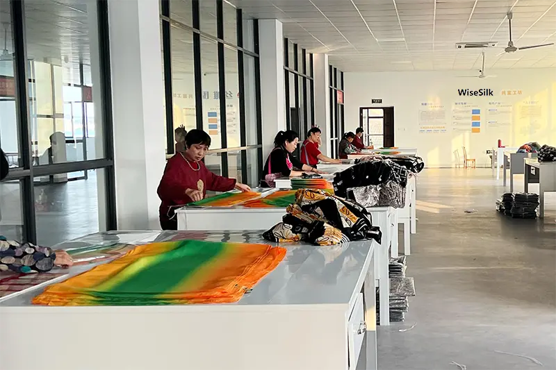 Factory worker inspecting silk scarves for quality during production