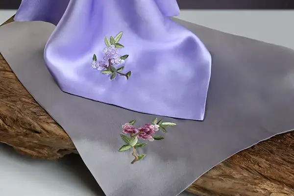Premium embroidery detail on silk fabric for branded accessories