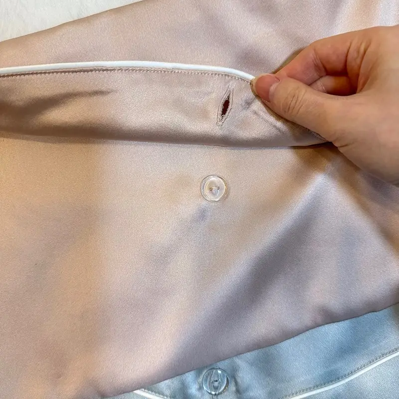 Button closure detail on a pink silk hair extension envelope bag