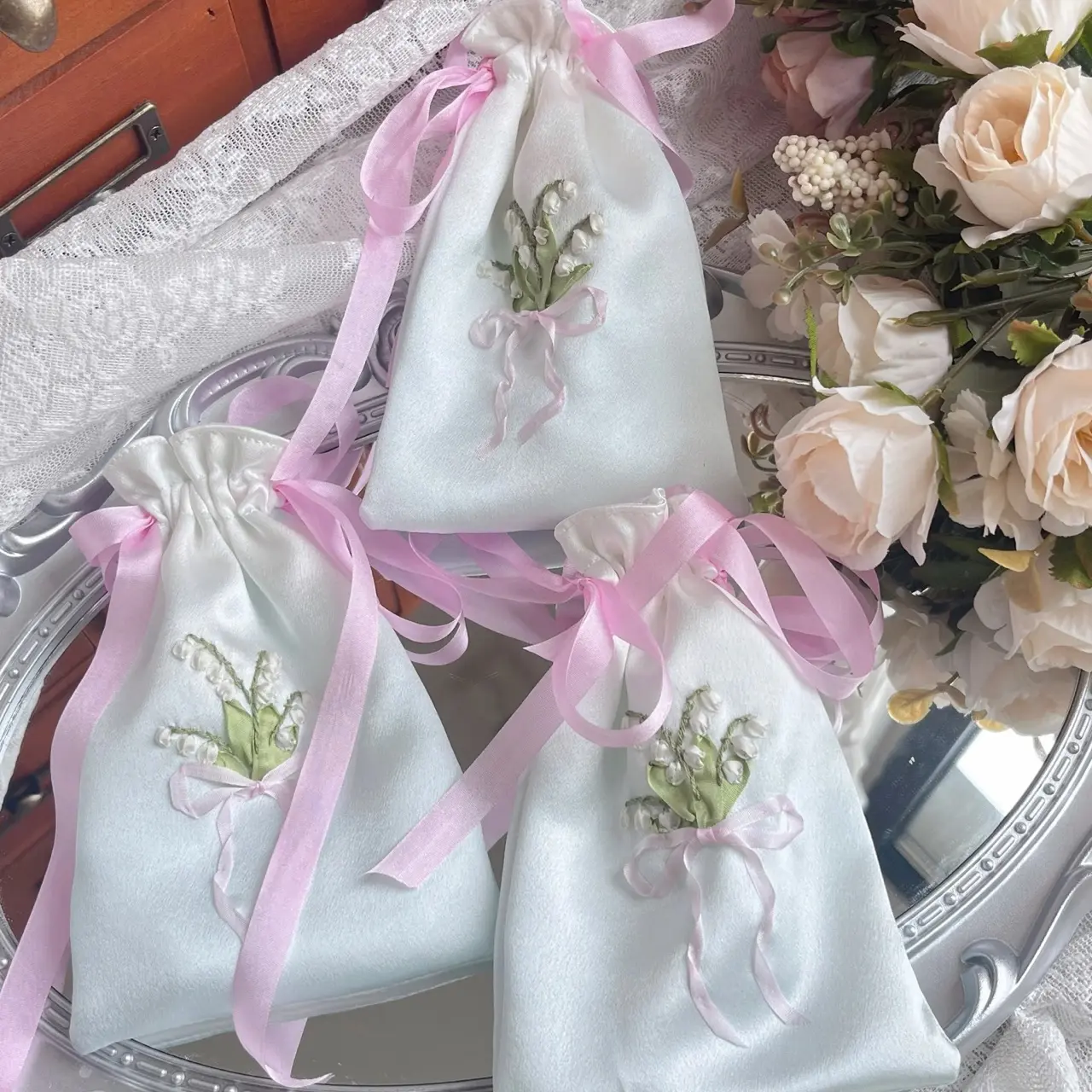 White silk wedding favor bags with pink ribbon embroidery